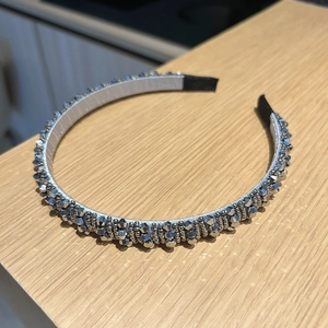 Détail d'un serre-tête argenté avec perles de cristal sur une surface en bois