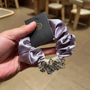 Detail of luxury pink satin scrunchie with crystal beads and elegant gold thread accents