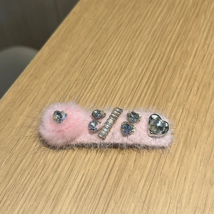 Gros plan d'une barrette en peluche rose avec cristaux en cœur et texture en fausse fourrure