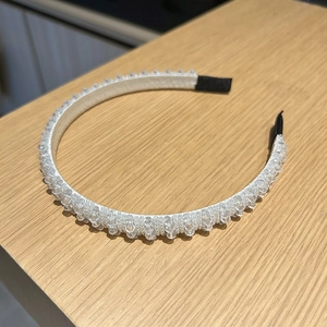 Détail d'un serre-tête en cristal fait main avec des perles transparentes sur tissu blanc