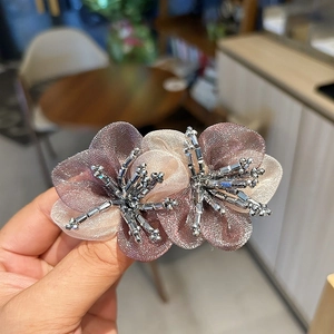 Detailed close-up of handmade organza flower hair clip with crystal bead embellishments