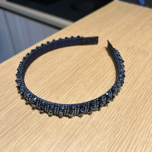 Détail d'un serre-tête à perles bleu foncé avec des cristaux sur un fond en bois