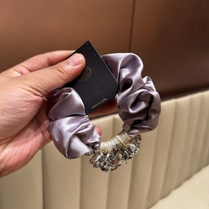 Detail of purple silk scrunchie with gold thread and faceted crystal pendant charms