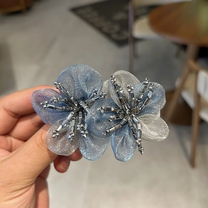 Detailed view of handmade organza flower hair clip with sparkling crystal center