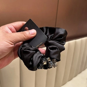 Close-up of black satin scrunchie with cluster of sparkling crystals on a display card