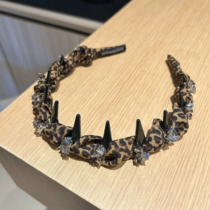 Detail of leopard print headband featuring black spikes, rhinestones and handmade label