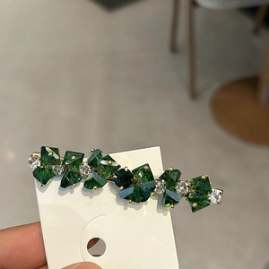 Nahaufnahme der smaragdgrünen Kristall-Haarspange mit Goldbasis und funkelnden Strasssteinen