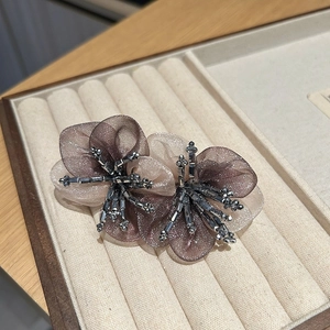 Detail of handmade organza flower hair clip with crystal beads on a velvet tray