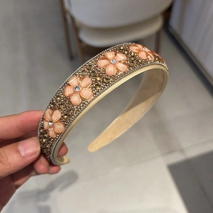 Détail du serre-tête cristal avec fleurs en résine pêche et strass dorés brillants