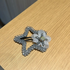 Détail de la pince à cheveux étoile en cristal bleu avec fleur en perles et pétales gris