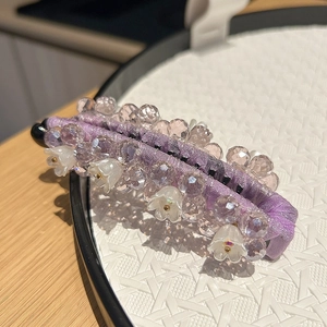 Gros plan d'une pince banane violette faite main avec perles et détails de muguet blanc
