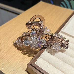 Detailed close-up of large hair claw clip with colorful crystal flowers on brown resin