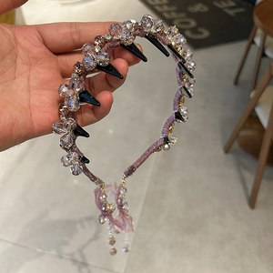 Vue détaillée d'un serre-tête en cristal violet avec base velours et glands perlés
