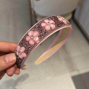 Détail d'un serre-tête rose en cristal avec fleurs œil-de-chat et strass brillants