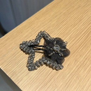 Détail de la pince à cheveux en forme d'étoile avec perles grises et fleur en résille