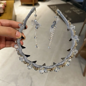 Détail d'un serre-tête en cristal bleu avec tissu plissé et long pendentif à pompon