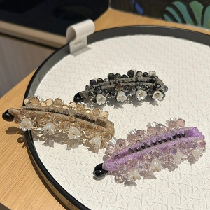 Détail de pinces banane perlées avec breloques fleurs en gris, champagne et lilas