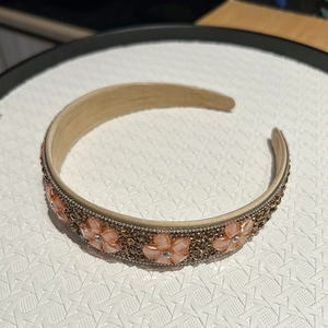 Détail du serre-tête en cristal avec perles brunes et breloques de fleurs orange