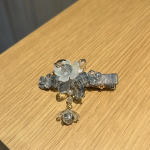 Detail of light blue floral crystal hair clip with elegant beaded drop pendant on wood
