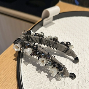 Détail de pinces bananes avec tissu en soie grise, perles noires et fleurs de muguet blanc