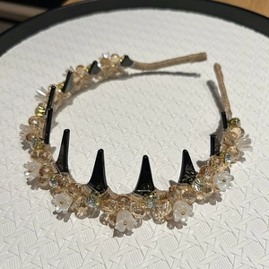 Detail of crystal headband with champagne beads, white petals and black punk spikes accents