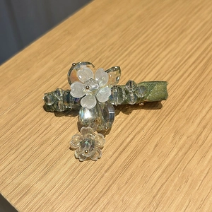 Detail of crystal flower hair clip with green satin ribbon and dangling blossom charm