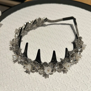 Detail of silver crystal beaded headband with white floral accents and black comb teeth