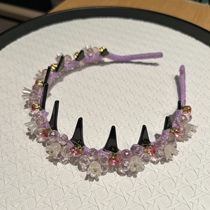 Detail view of purple fabric headband with pink rhinestones and black punk spikes