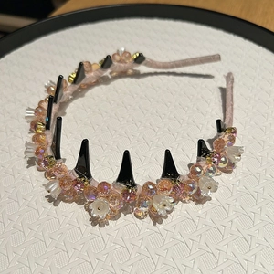 Detail of pink satin headband with iridescent beads, white flowers, and black metal studs
