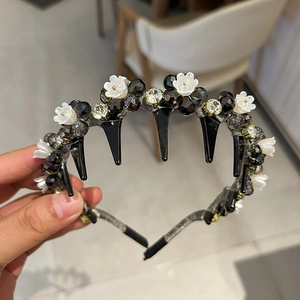 Close-up of black headband with white 3D flowers and faceted beads featuring inner comb teeth