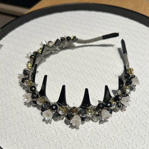 Detail of crystal headband with black spikes and delicate white floral accents