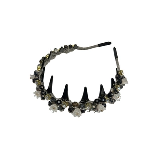 Gothic style crystal headband with black spikes and white floral charms on dark fabric