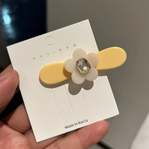 Détail d'une jolie pince à cheveux fleur en acétate avec strass sur carte de présentation