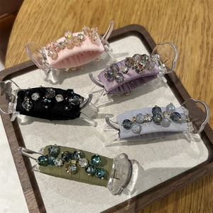 Detailed close-up of 5 colorful silk ponytail clips with crystals on a wooden tray