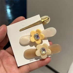 Vue détaillée des barrettes à fleurs en acétate avec strass sur carte de support