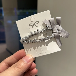Barrette à cheveux élégante avec perles argentées et nœud gris sur carte support