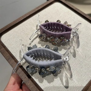 Detail view of large crystal hair claw clips in purple and grey-blue silk finish