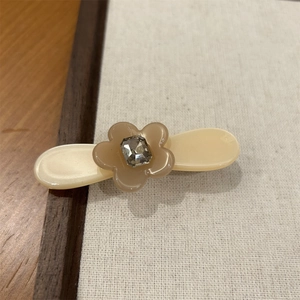 Détail de la pince à cheveux fleur en acétate avec strass carré sur base ovale crème