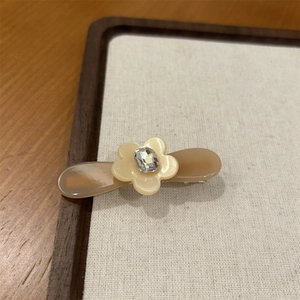 Vue détaillée de la pince à cheveux fleur en acétate avec strass et pince bec de canard