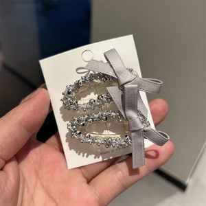 Détail de pinces à cheveux à perles argentées avec un nœud en satin gris sur une carte