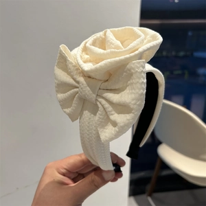 Detailed view of handmade cream floral headband with 3D fabric rose and layered bow design