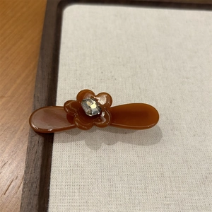 Gros plan d'une pince à cheveux fleur marron caramel avec détail en strass étincelant