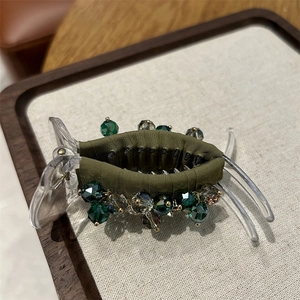 Detail of olive green satin hair claw with faceted green crystals and clear plastic clip