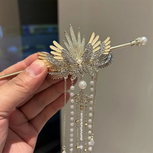 Detail of golden phoenix wing hair stick with rhinestone inlay and long pearl tassels