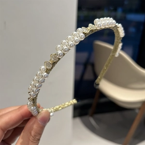 Close-up of golden baroque headband with double rows of pearls and rhinestone bows