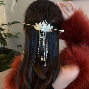 Detailed view of wing-shaped tassel hair pin with pearls on a model's long hair