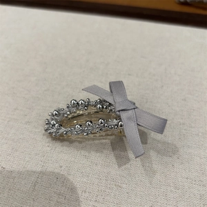 Détails de perles argentées et nœud en ruban gris sur une pince à cheveux chic