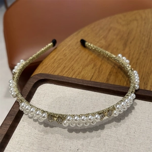 Detailed close-up of a baroque pearl headband with sparkling rhinestones and golden frame
