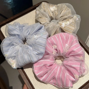 Detailed view of large organza scrunchies with stripe fabric and white floral details