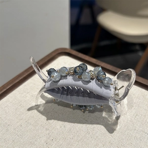 Detailed view of large grey fabric hair claw clip with sparkling crystal bead embellishments